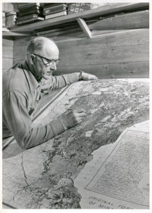 Bill Trygg Sr. studying historical maps showing original forests of Minnesota, 1956.